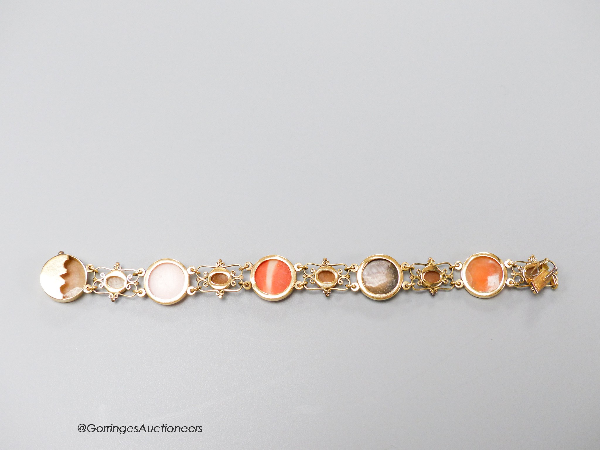 A 14k yellow metal, multi carved cameo and flowerhead set bracelet, including paua shell, shell and coral, carved with the busts of ladies, to dexter and sinister, 16.5cm, gross weight 13.5 grams.